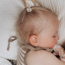 Toddle lying on a soft surface with a tiny brown and white gingham bow in hair