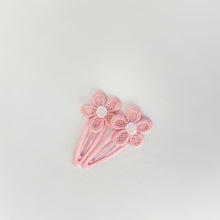 Two pink flower-shaped hair clips with pink lace petals and white centers, arranged on a light gray background.