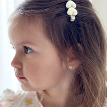 Close-up of a brunette pre-school aged girl with a decorative hair clip embellished with off-white, ribbed fabric covered hearts.