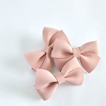 Three dusty pink faux-suede bow hair clips arranged on a clean white background.